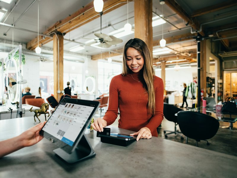 A shopper paying by card at a tablet point-of-sale counter in a boutique